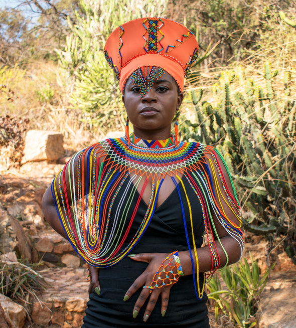 African lady wearing beaded Zulu hat, beaded headband, shawl necklace and  Zulu beaded finger bracelet.